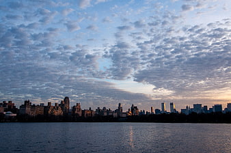 Manhattan Skyline at Dusk Over Lake with Cloudy Sky