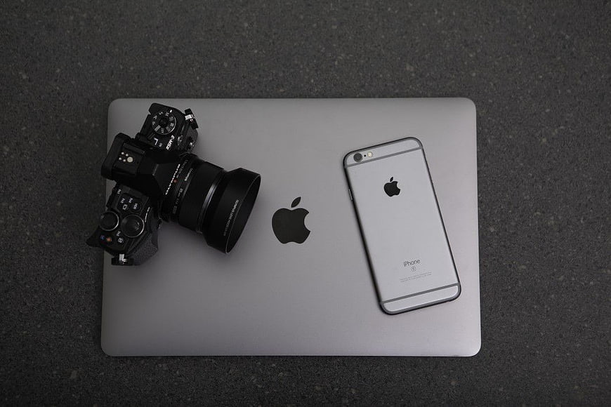 Top View of Camera, iPhone, and MacBook on Dark Surface