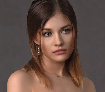 Portrait of a young woman with brown hair and gold earrings