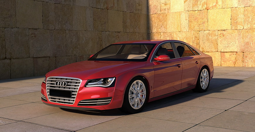 Red Audi A8 luxury sedan parked against stone wall