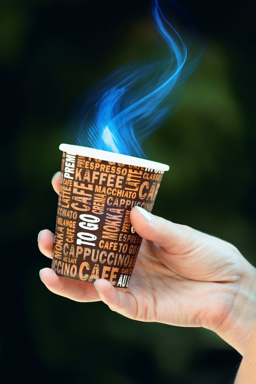 Hand holding coffee cup with magical blue steam