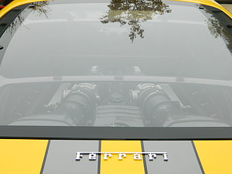 Rear engine view of yellow Ferrari with racing stripes