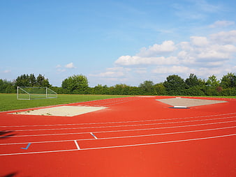 Red athletics track with sand pits and blue sky