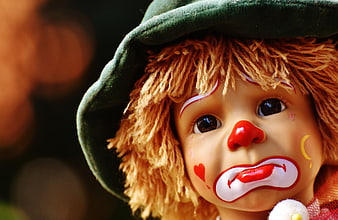 Close-up of a sad clown doll with green hat and yarn hair
