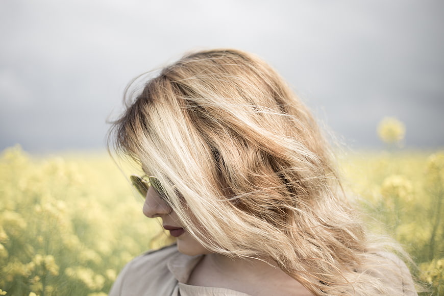 Blonde Woman with Windblown Hair in Yellow Flower Field