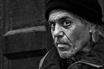 Black and white portrait of elderly homeless man with intense gaze