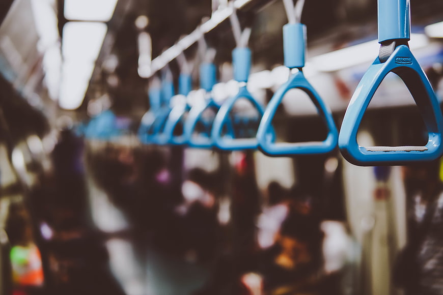 Blue subway hand straps hanging in a blurred train interior
