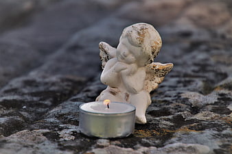 Weathered Angel Statue and Candle on Stone Tombstone