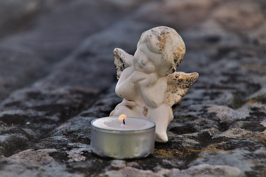 Weathered Angel Statue and Candle on Stone Tombstone