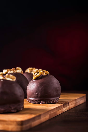Gourmet chocolate truffles with walnuts on wooden board