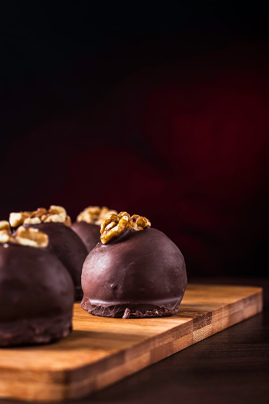 Gourmet chocolate truffles with walnuts on wooden board