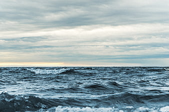 Moody ocean waves under cloudy sky with horizon