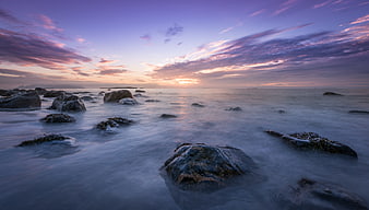 Serene Sunset Seascape with Smooth Misty Water and Rocks