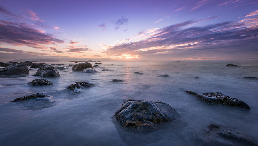 Serene Sunset Seascape with Smooth Misty Water and Rocks