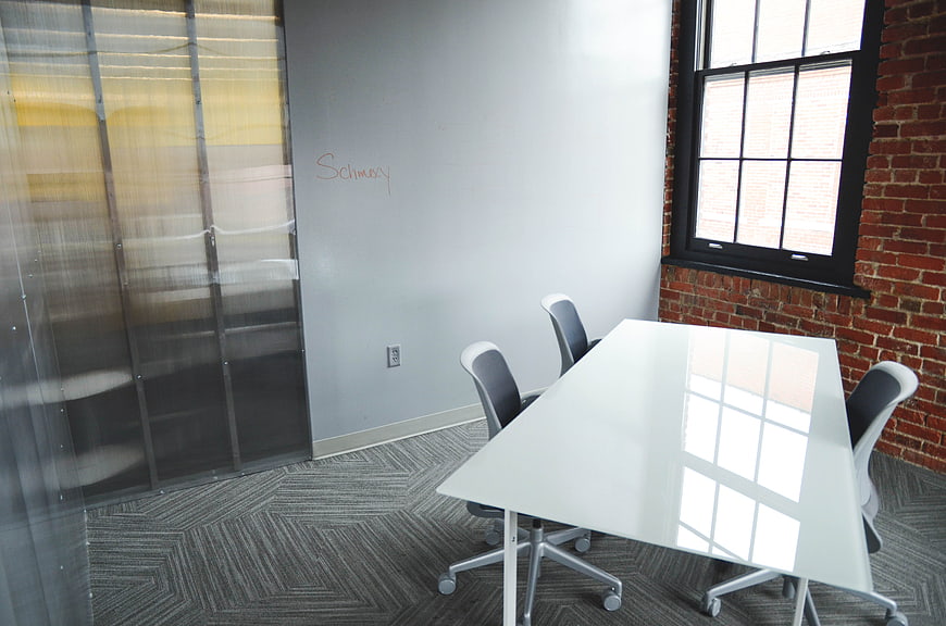 Modern office meeting room with white table and brick wall