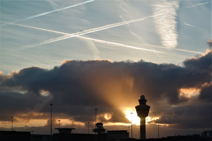 Dramatic sunset over airport control tower with contrails