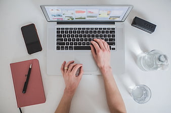 Top View of Hands Typing on Laptop at White Desk