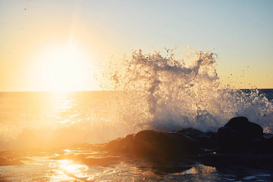 Ocean Wave Splashing on Rocks at Golden Sunset