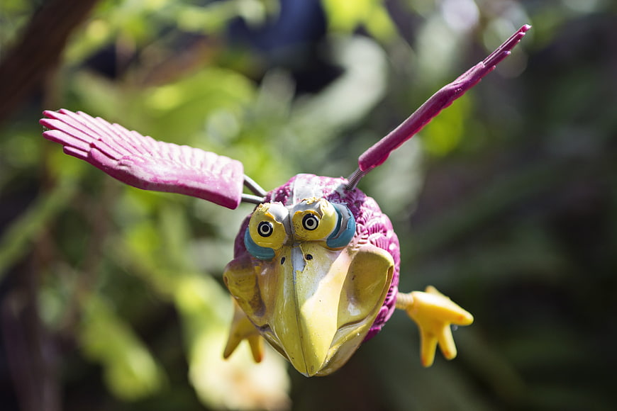 Colorful purple and yellow bird garden ornament in flight