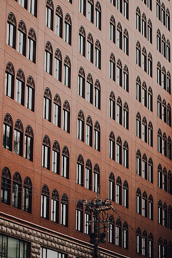 Red brick building facade with arched windows and utility pole