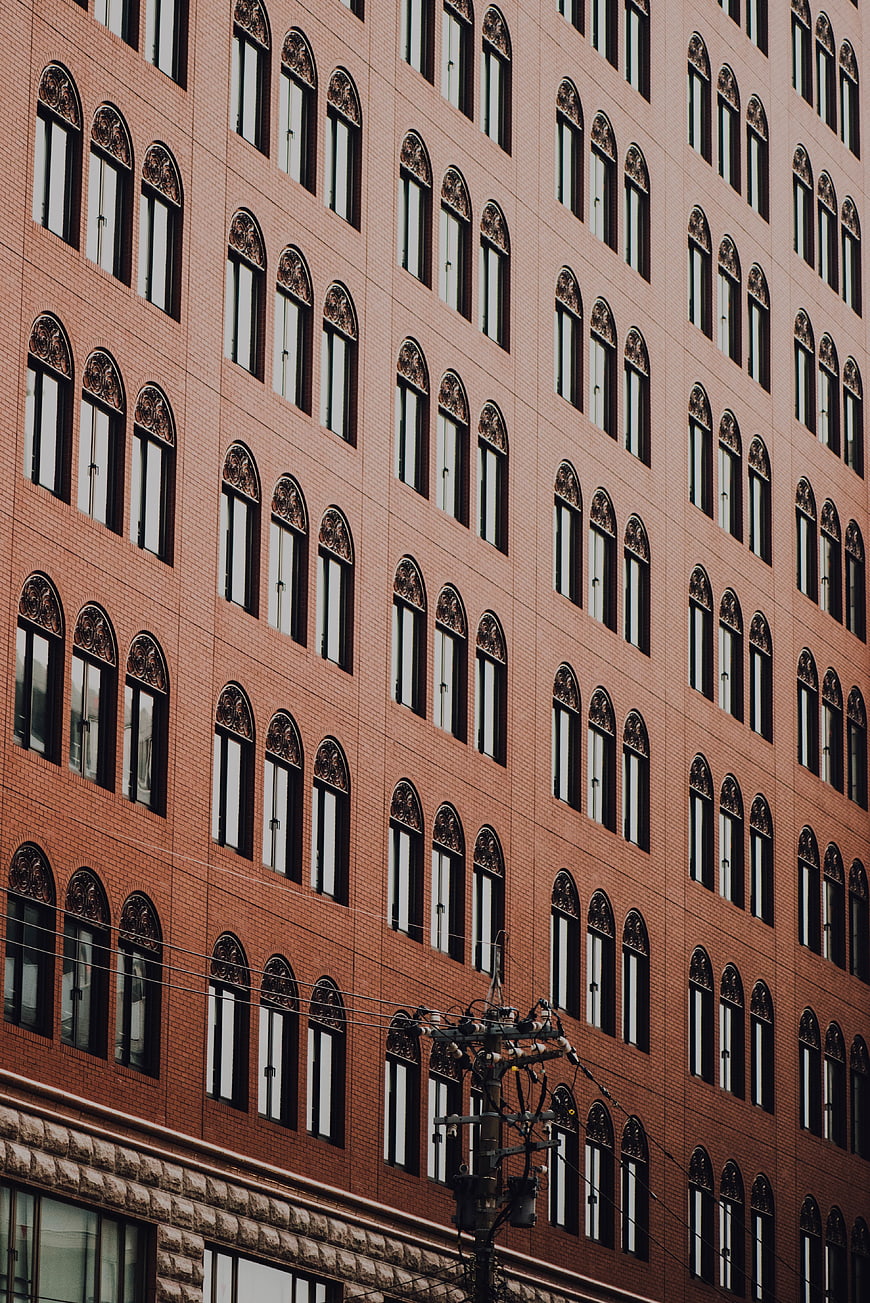 Red brick building facade with arched windows and utility pole