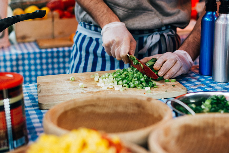 Chef chopping green onions on wooden cutting board