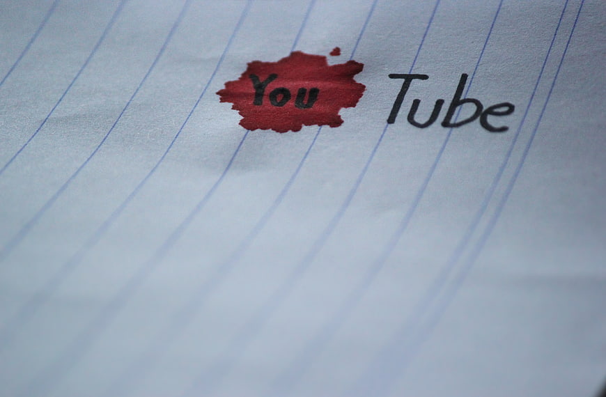 Handwritten YouTube text with red ink blot on lined paper