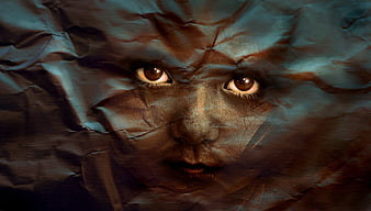Surreal portrait of child's face emerging from crumpled paper texture