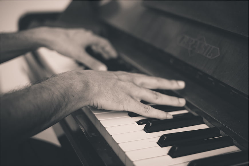 Close-up of hands playing piano keys in monochrome