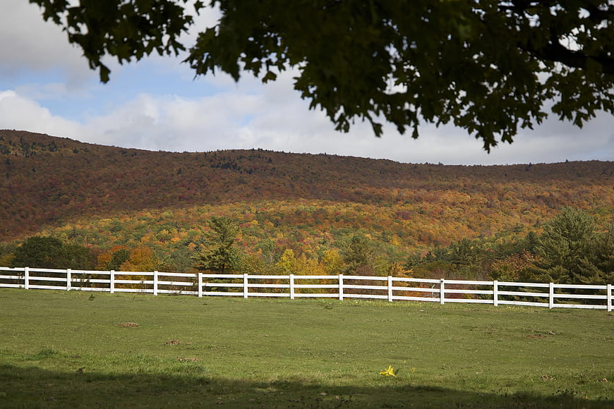 White Fence in Green Pasture with Autumn Mountain View