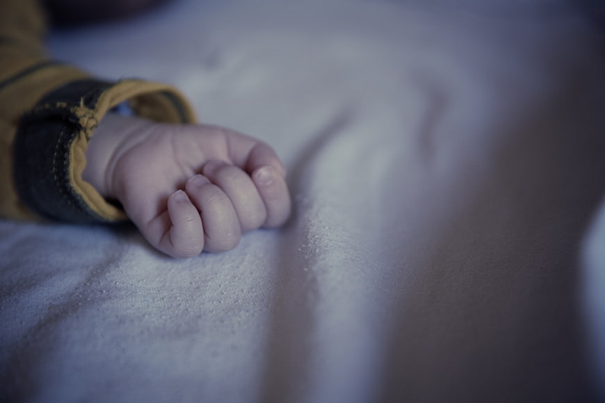 Close-up of baby hand resting on white blanket