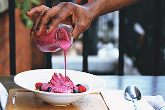 Hand Pouring Berry Sauce Over Fruit Dessert In Restaurant