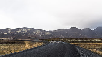 Winding gravel road through desolate highland landscape with mountains