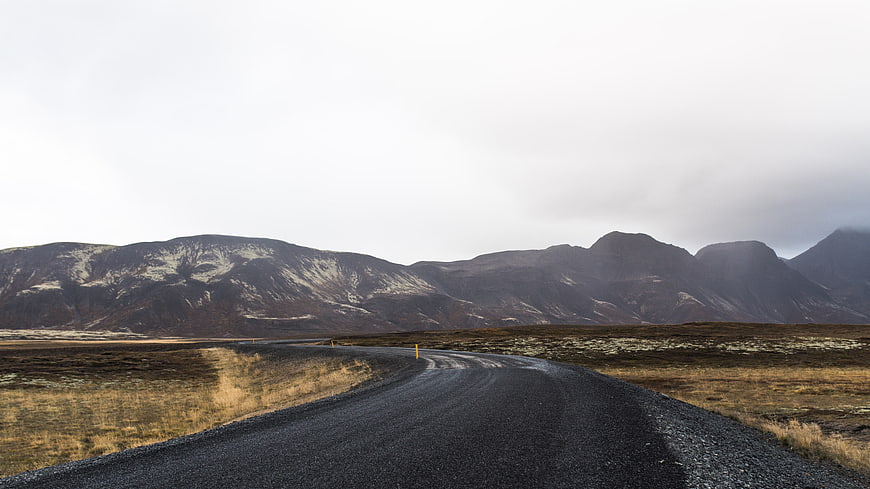 Winding gravel road through desolate highland landscape with mountains