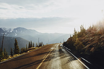 Winding Mountain Road with Snow-Capped Peaks and Sunlight