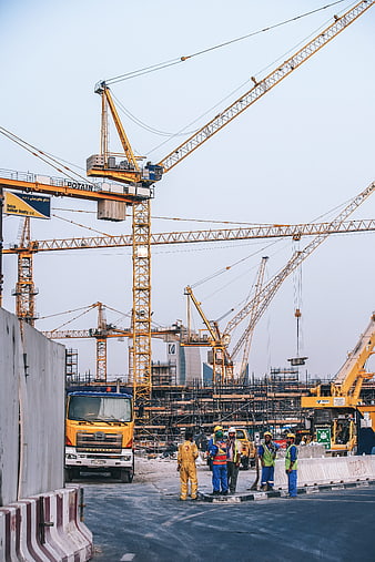 Construction workers and cranes at a large industrial building site