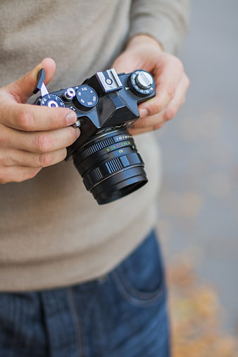 Hands holding vintage black film camera outdoors
