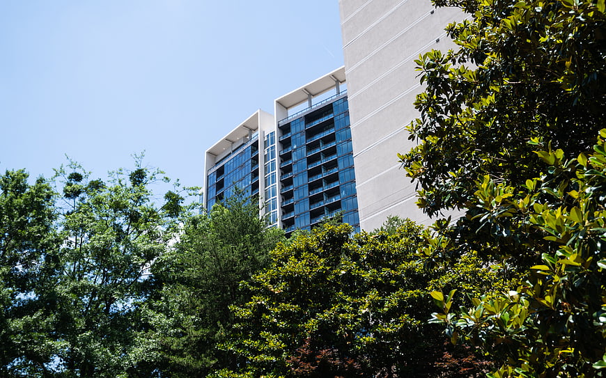 Modern Apartment Building with Blue Glass Windows Behind Green Trees