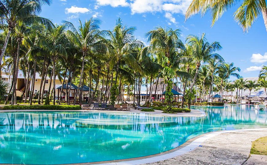Tropical resort swimming pool with palm trees and blue sky