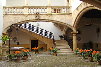 Historic Spanish Courtyard With Stone Staircase And Orange Flowers