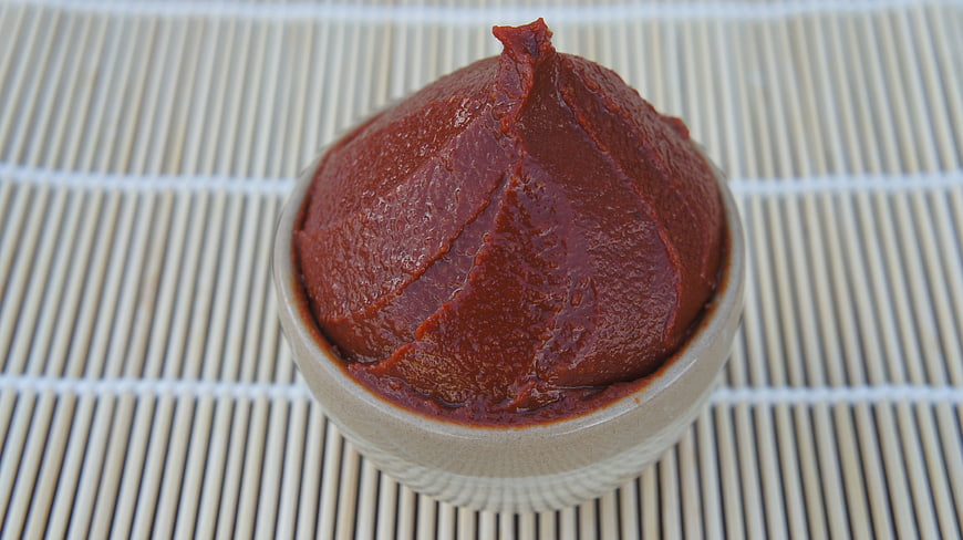 Traditional Korean Red Bean Paste in Ceramic Bowl on Bamboo Mat