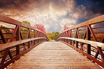Wooden Bridge Over River in Autumn with Dramatic Sky