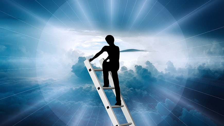 Silhouette of man climbing ladder into clouds and light