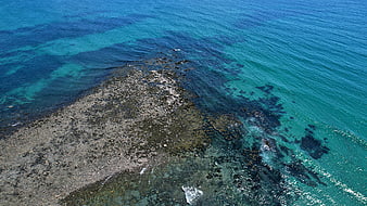 Aerial View of Rocky Coastline in Turquoise Ocean Water