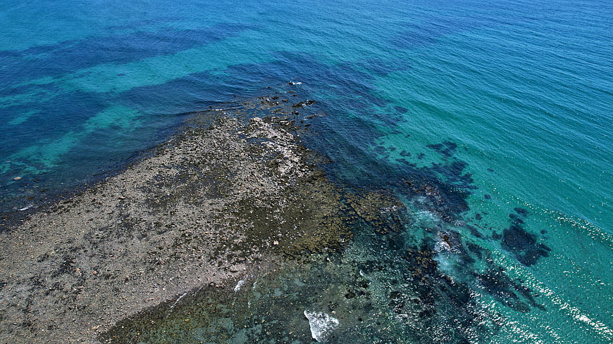 Aerial View of Rocky Coastline in Turquoise Ocean Water