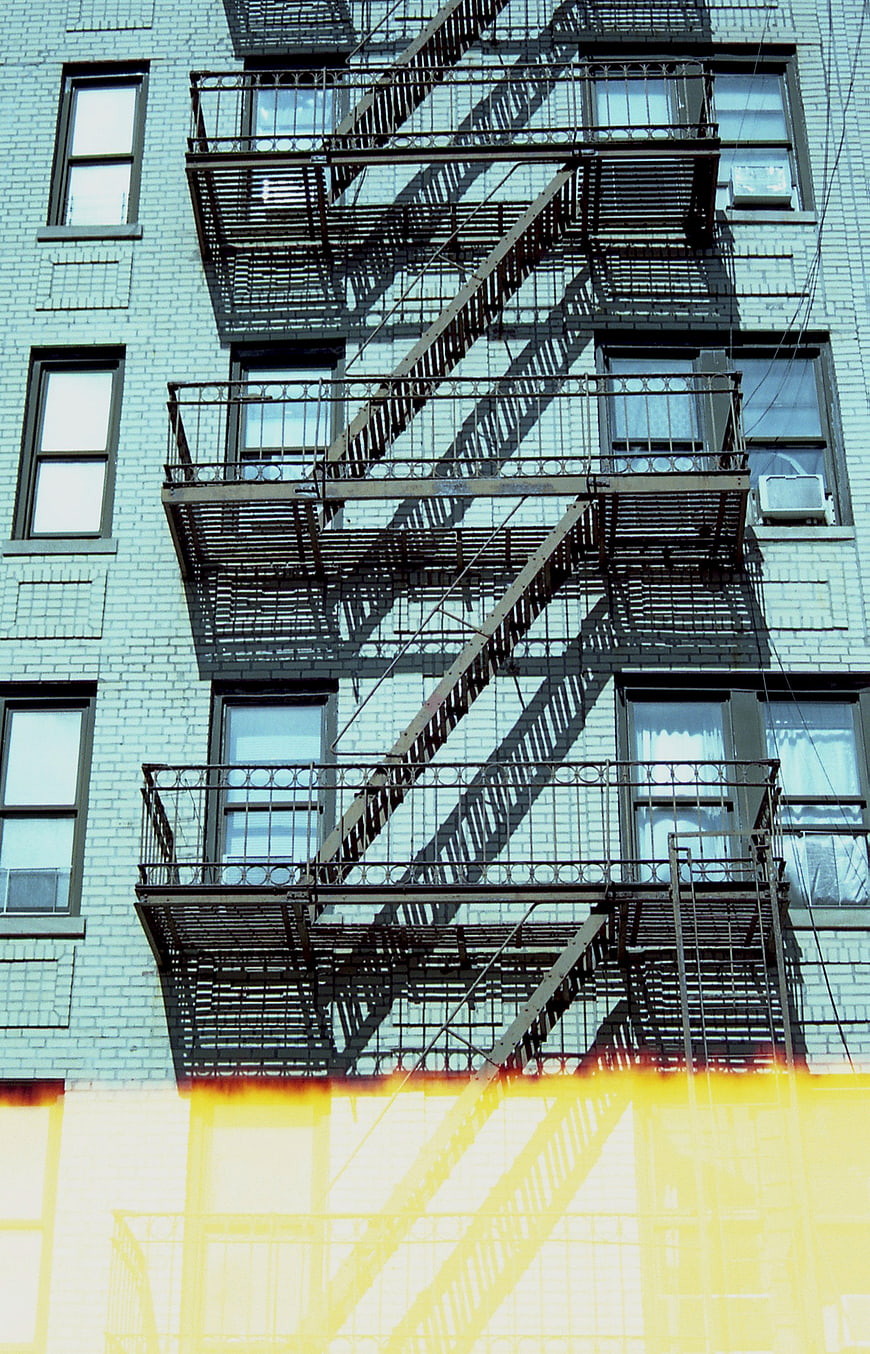 Urban Fire Escape on Blue Brick Building with Yellow Gradient