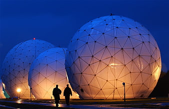 Illuminated Radar Domes at Dusk with Silhouetted Figures