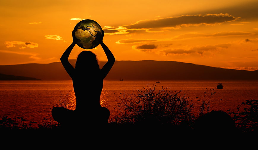 Silhouette of woman holding globe at sunset