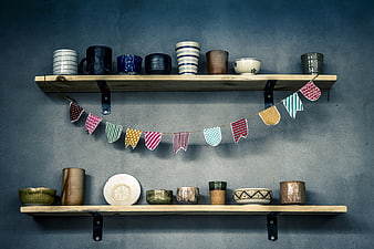 Handmade pottery on wooden shelves with bunting flags