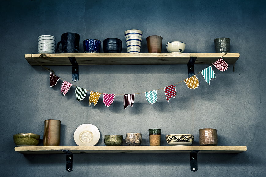 Handmade pottery on wooden shelves with bunting flags